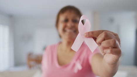 Smiling-african-american-senior-woman-wearing-pink-t-shirt-holding-pink-breast-cancer-ribbon