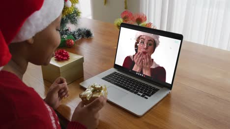 Afroamerikanische-Frau-Mit-Weihnachtsmütze-Nutzt-Laptop-Für-Weihnachtsvideoanruf,-Mit-Freund-Auf-Dem-Bildschirm