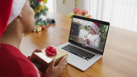 Afroamerikanische-Frau-Mit-Weihnachtsmütze-Nutzt-Laptop-Für-Einen-Weihnachtsvideoanruf-Mit-Einem-Jungen-Auf-Dem-Bildschirm