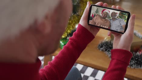 Caucasian-man-using-smartphone-for-christmas-video-call,-with-smiling-family-on-screen