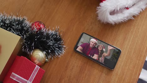 Lächelndes-Kaukasisches-Paar-Mit-Weihnachtsmützen-Bei-Weihnachtsvideoanruf-Auf-Dem-Smartphone