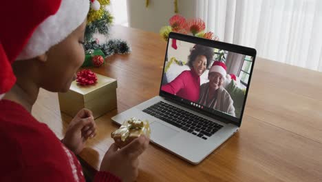 African-american-woman-with-santa-hat-using-laptop-for-christmas-video-call-with-family-on-screen
