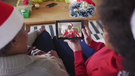 Afroamerikanische-Mutter-Und-Tochter-Nutzen-Ein-Tablet-Für-Einen-Weihnachtsvideoanruf-Mit-Dem-Weihnachtsmann-Auf-Dem-Bildschirm