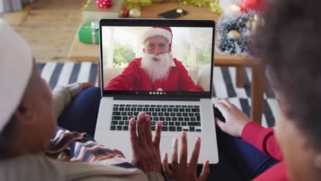 African-american-mother-and-daughter-using-laptop-for-christmas-video-call-with-santa-on-screen