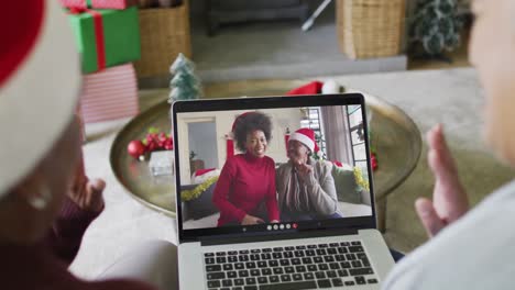 Senior-diverse-female-friends-using-laptop-for-christmas-video-call-with-smiling-friends-on-screen