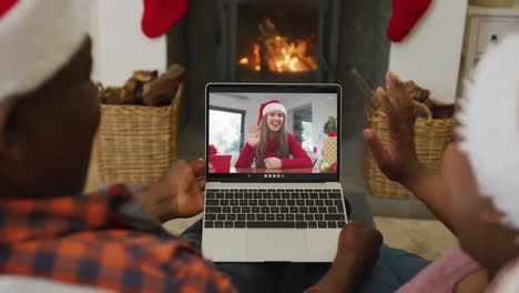 Afroamerikanisches-Paar-Mit-Weihnachtsmützen-Nutzt-Laptop-Für-Weihnachtsvideoanruf-Mit-Frau-Auf-Dem-Bildschirm