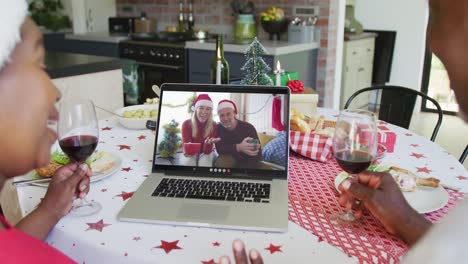 Afroamerikanisches-Paar-Mit-Wein-Und-Laptop-Für-Weihnachtsvideoanruf-Mit-Glücklichem-Paar-Auf-Dem-Bildschirm