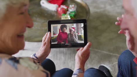 Senior-caucasian-couple-using-tablet-for-christmas-video-call-with-smiling-family-on-screen