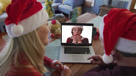Caucasian-couple-with-santa-hats-using-laptop-for-christmas-video-call-with-woman-on-screen