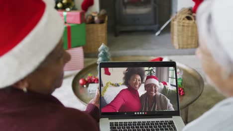 Smiling-diverse-senior-female-friends-using-laptop-for-christmas-video-call-with-family-on-screen
