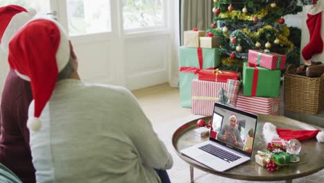 Two-senior-diverse-female-friends-using-laptop-for-christmas-video-call-with-man-on-screen
