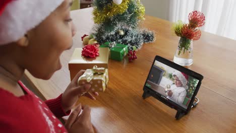 Afroamerikanische-Frau-Mit-Weihnachtsmütze-Nutzt-Tablet-Für-Weihnachtsvideoanruf,-Mit-Junge-Auf-Dem-Bildschirm