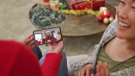 Smiling-asian-couple-using-smartphone-for-christmas-video-call-with-happy-woman-on-screen