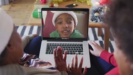 African-american-mother-and-daughter-using-laptop-for-christmas-video-call-with-boy-on-screen