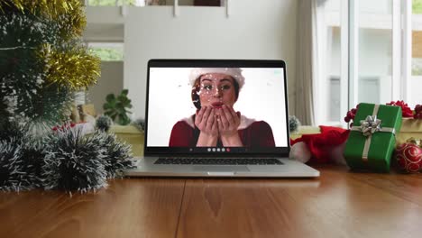 Smiling-caucasian-woman-wearing-santa-hat-on-christmas-video-call-on-laptop
