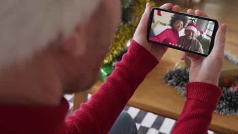 Caucasian-man-using-smartphone-for-christmas-video-call,-with-smiling-family-on-screen