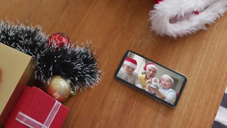 Lächelnde-Kaukasische-Familie-Mit-Weihnachtsmützen-Bei-Weihnachtsvideoanruf-Auf-Dem-Smartphone