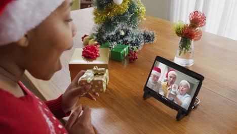 Afroamerikanische-Frau-Mit-Weihnachtsmütze-Nutzt-Tablet-Für-Weihnachtsvideoanruf-Mit-Der-Familie-Auf-Dem-Bildschirm