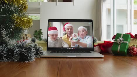 Smiling-caucasian-family-wearing-santa-hats-on-christmas-video-call-on-laptop