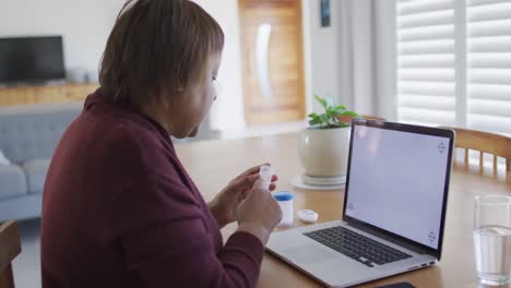 African-american-senior-woman-making-laptop-video-call-and-holding-medication,-copy-space-on-screen