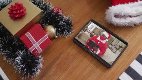 African-american-man-wearing-santa-costume-on-christmas-video-call-on-tablet