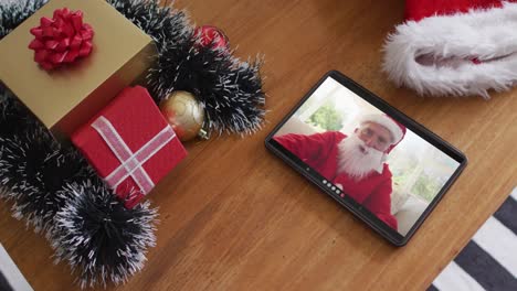 Smiling-caucasian-man-wearing-santa-costume-on-christmas-video-call-on-tablet