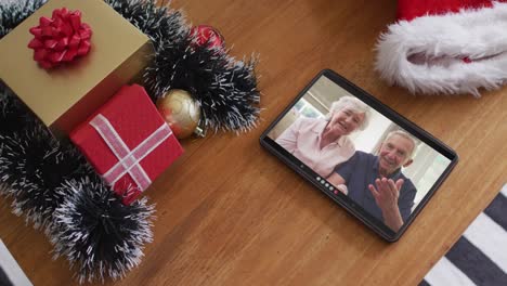 Smiling-senior-caucasian-couple-on-christmas-video-call-on-tablet