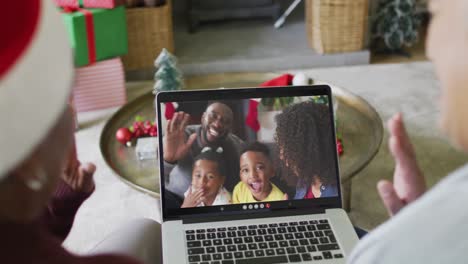Diverse-senior-female-friends-using-laptop-for-christmas-video-call-with-family-on-screen