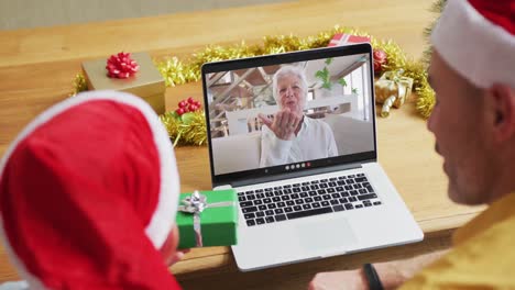 Kaukasischer-Vater-Und-Sohn-Mit-Weihnachtsmützen-Mit-Laptop-Für-Weihnachtsvideoanruf-Mit-Frau-Auf-Dem-Bildschirm
