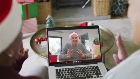 Diverse-senior-female-friends-using-laptop-for-christmas-video-call-with-man-on-screen