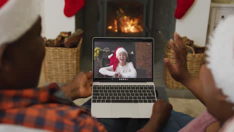 African-american-couple-with-santa-hats-using-laptop-for-christmas-video-call-with-woman-on-screen