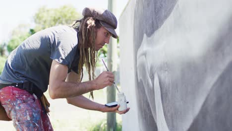 Video-of-caucasian-male-artist-with-dreadlocks-painting-whale-mural-on-wall