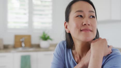 Porträt-Einer-Glücklichen-Asiatischen-Frau,-Die-In-Der-Küche-Sitzt