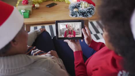 African-american-mother-and-daughter-using-tablet-for-christmas-video-call-with-woman-on-screen