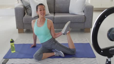 Happy-asian-woman-on-mat,-exercising,-making-fitness-vlog-from-home