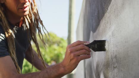 Video-of-caucasian-male-artist-with-dreadlocks-using-paintbrush-painting-whale-mural-on-wall