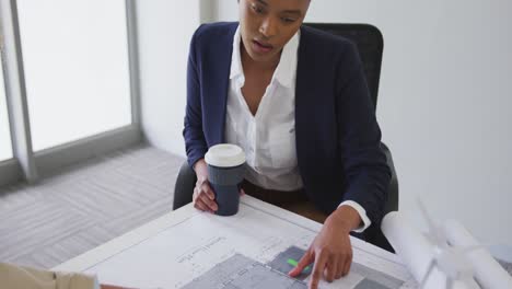 Biracial-female-architects-talking-and-checking-architects-plans-in-modern-office