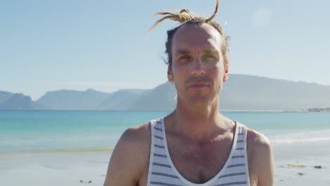 Video-portrait-of-smiling-caucasian-man-with-dreadlocks-standing-on-sunny-beach