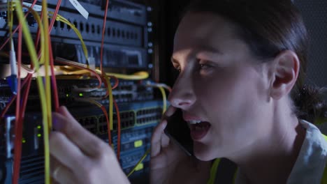 Caucasian-female-it-technician-using-smartphone-checking-computer-server