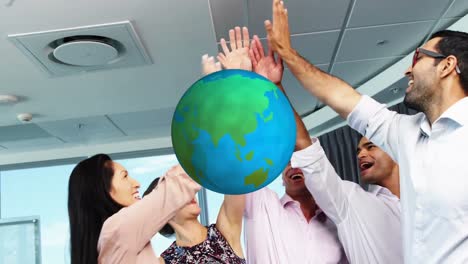 Animation-of-globe-over-work-colleagues-high-fiving-in-background