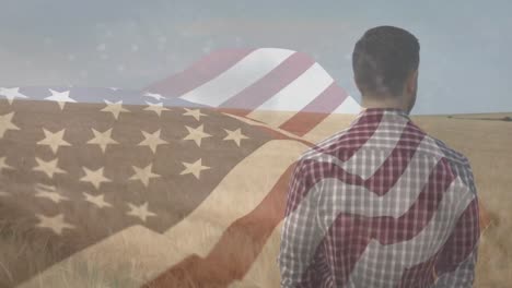Animation-of-flag-of-america-blowing-over-male-farmer-standing-in-field-of-wheat