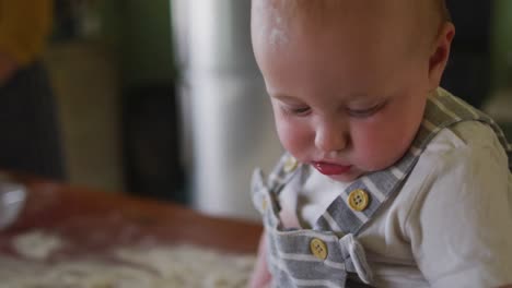Porträt-Eines-Glücklichen-Kaukasischen-Babys,-Das-In-Der-Küche-In-Die-Kamera-Blickt