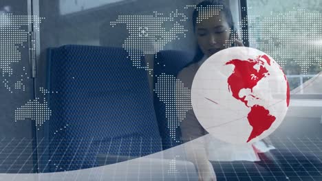 Animation-of-red-and-white-globe-and-map,-over-businesswoman-using-phone-and-laptop-on-train
