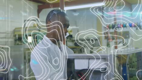 Animation-of-white-lines-over-african-american-male-scientist-working-in-lab