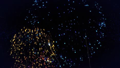 Animation-of-happy-new-year-text-in-blue-with-colourful-new-year-fireworks-exploding-in-night-sky