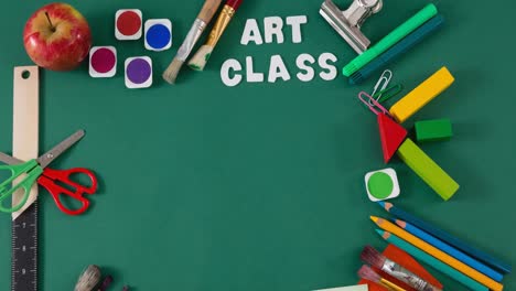 Animation-of-art-class-text-over-apple-and-art-and-crafts-equipment-on-green-table-top