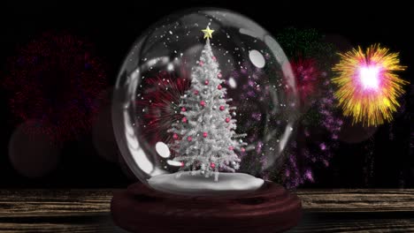 Animation-of-decorated-christmas-tree-in-snow-globe-and-colourful-fireworks-exploding-in-night-sky