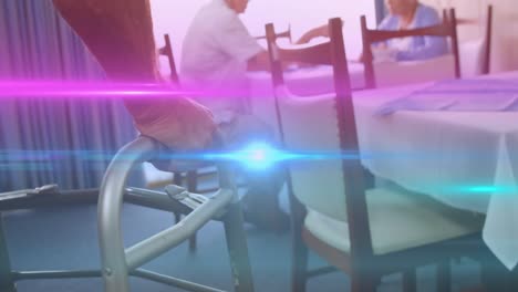 Animation-of-coloured-lights-moving-over-senior-man-in-dining-room-using-walking-frame