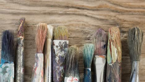 Animation-of-row-of-used-paintbrushes-on-wooden-surface