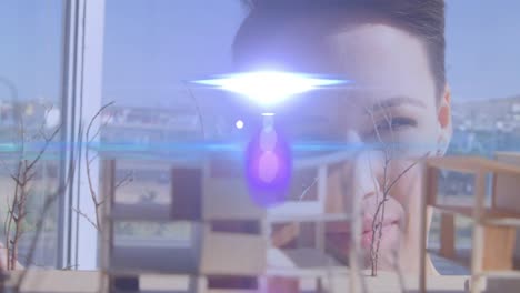 Animation-of-pink-and-blue-light-beams-flaring-over-female-architect-looking-at-architectural-model